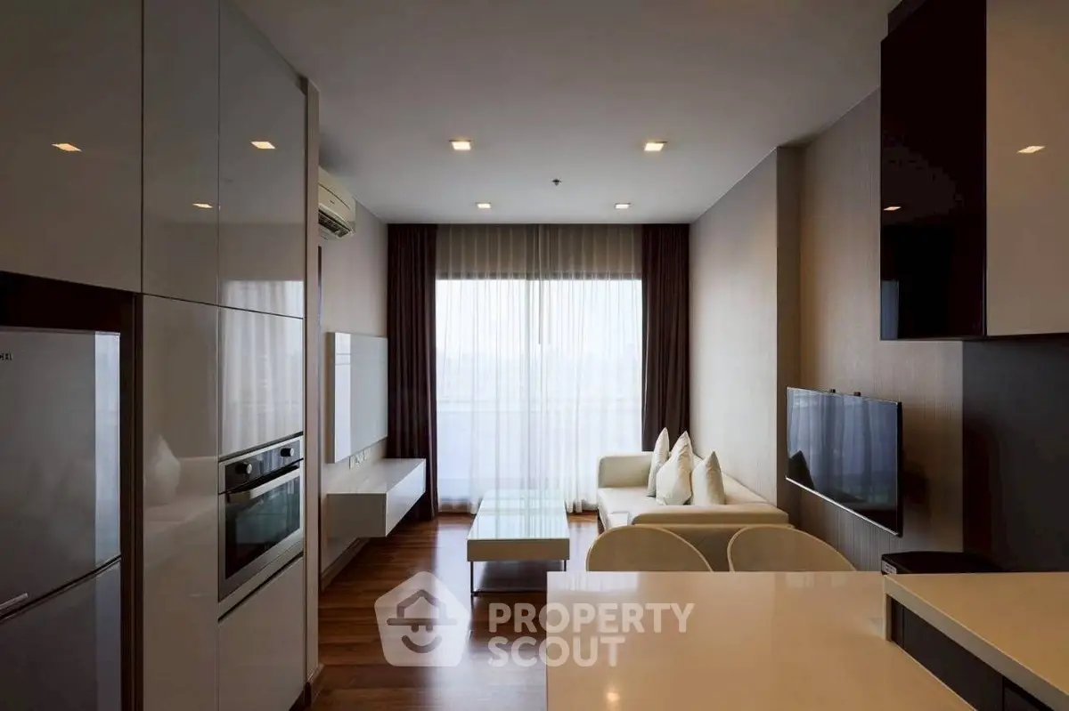 Modern living room with sleek design, featuring a wall-mounted TV, cozy sofa, and stylish kitchen area.