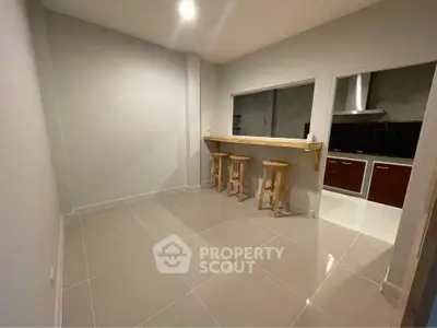 Modern kitchen with breakfast bar and stools, sleek tile flooring, and open layout.