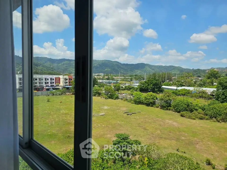 Stunning view from window overlooking lush green landscape and distant mountains.