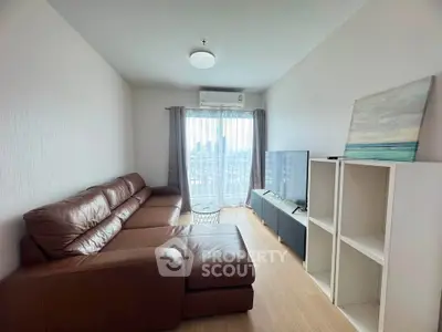 Modern living room with leather sofa and city view, featuring sleek TV setup and natural light.
