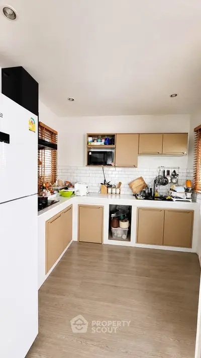 Modern kitchen with sleek cabinets and wooden flooring, featuring a spacious layout and contemporary appliances.