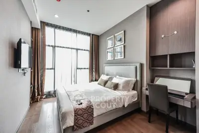 Modern bedroom with elegant decor, large window, and cozy workspace in a stylish apartment.