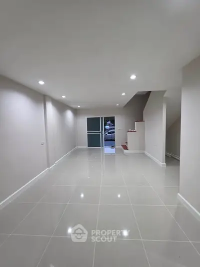 Spacious modern interior with glossy tiled floors and recessed lighting, ideal for versatile living space.