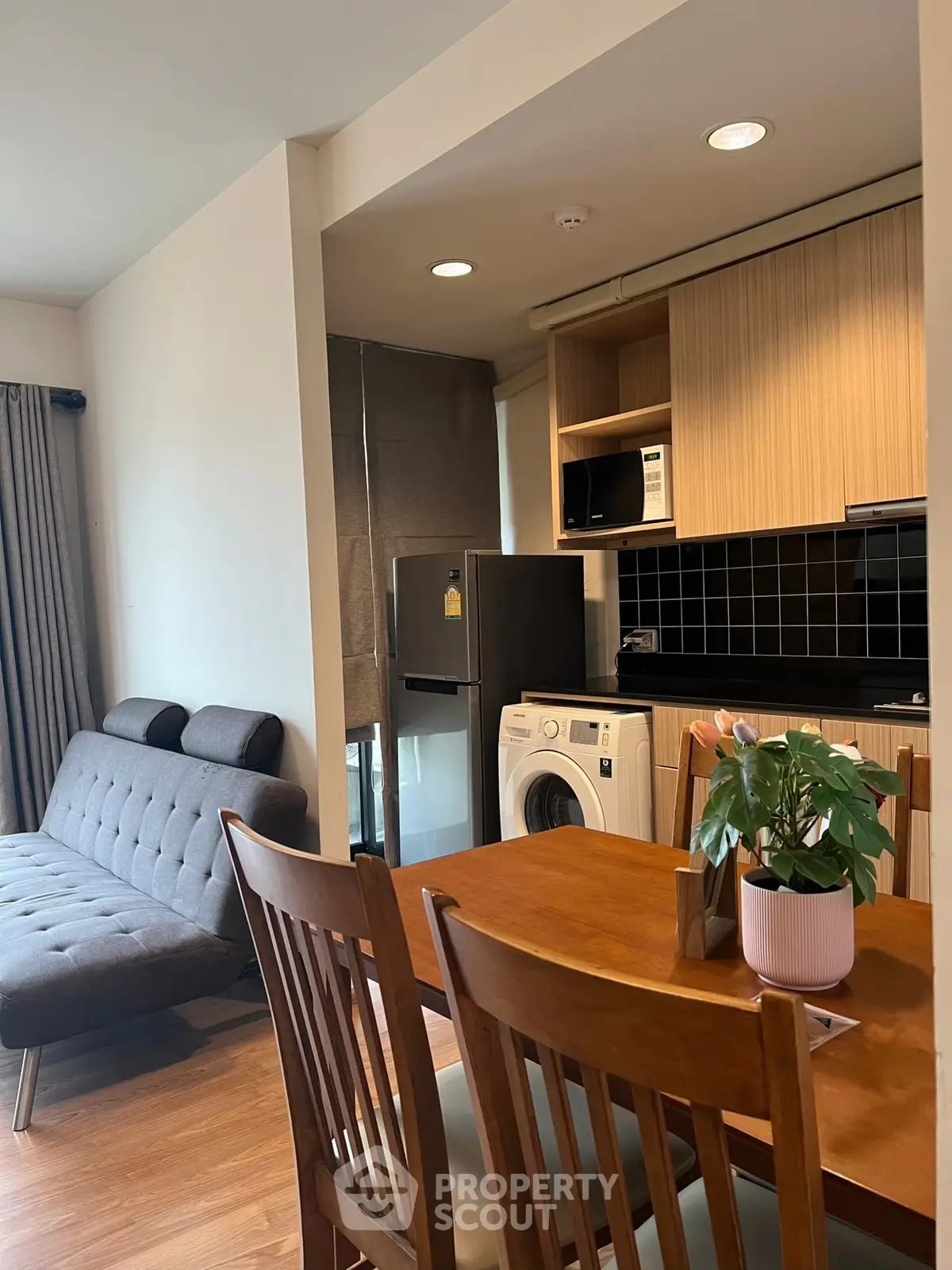 Modern open-plan living room with kitchen featuring washing machine and stylish decor.