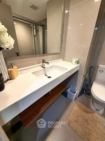 Modern bathroom with sleek sink and toilet, featuring elegant tiles and contemporary fixtures.