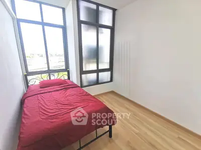 Cozy bedroom with large windows and natural light, featuring a single bed and minimalist design.
