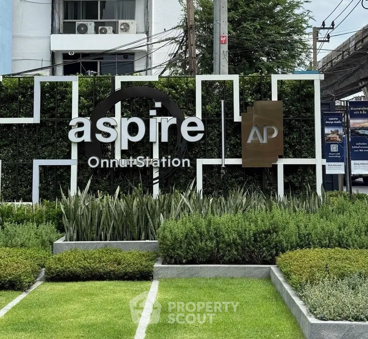 Modern condominium entrance with lush landscaping at Aspire Onnut Station.