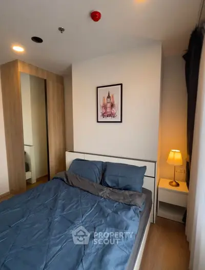 Cozy bedroom with modern decor and stylish lighting, featuring a comfortable bed and mirrored wardrobe.