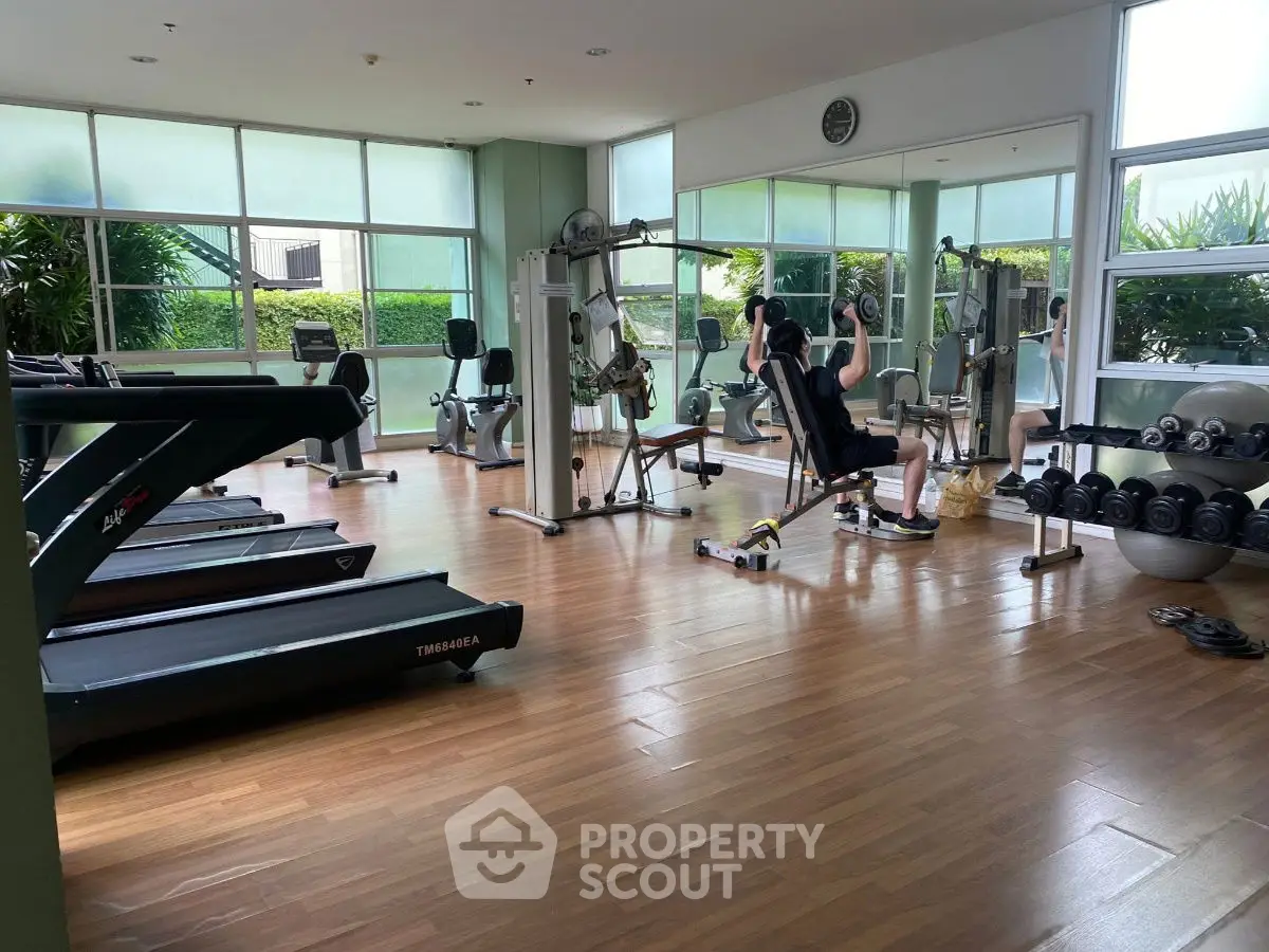 Spacious gym with modern equipment and large windows for natural light.