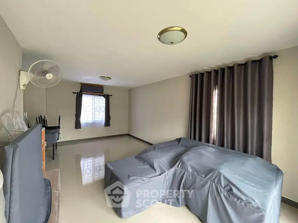 Spacious living room with large windows draped in elegant dark curtains, reflecting a comfortable and serene atmosphere, perfect for relaxation.