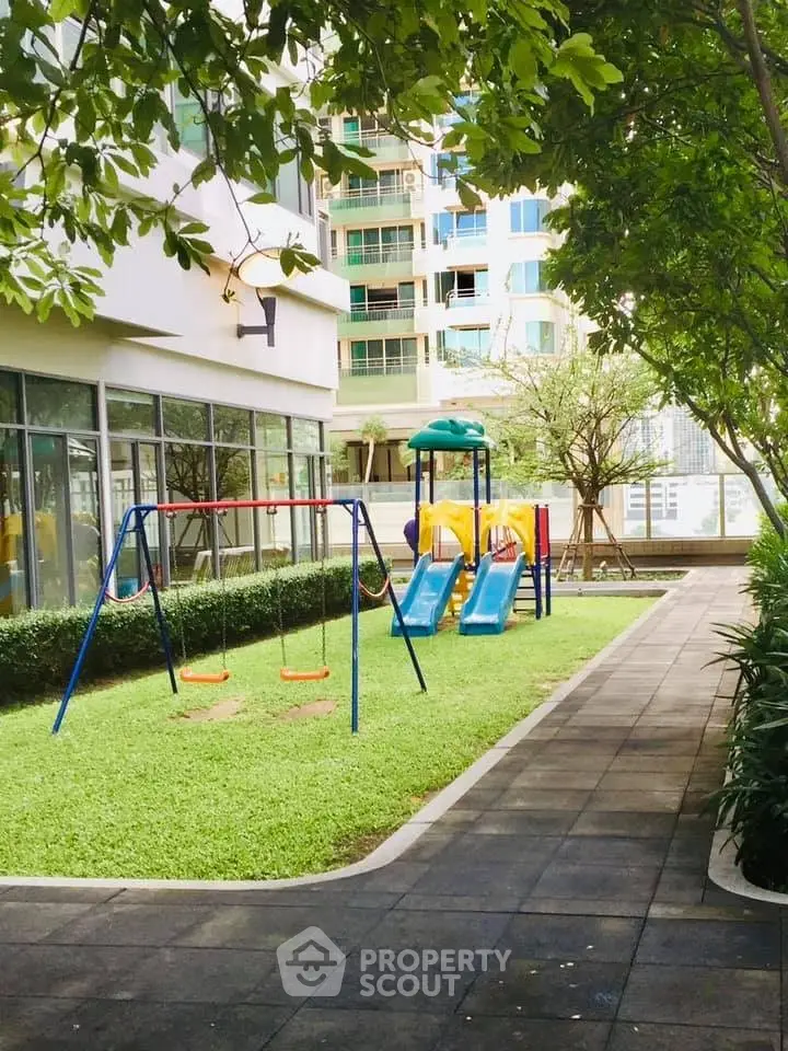 Modern residential building with lush garden and children's playground, ideal for family living.