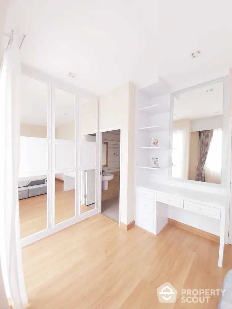 Bright and spacious bedroom with elegant wooden flooring and built-in wardrobe