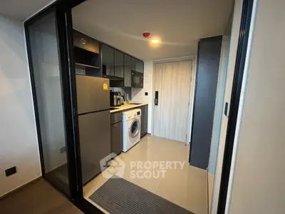 Modern compact kitchen with washing machine and sleek appliances in stylish apartment.