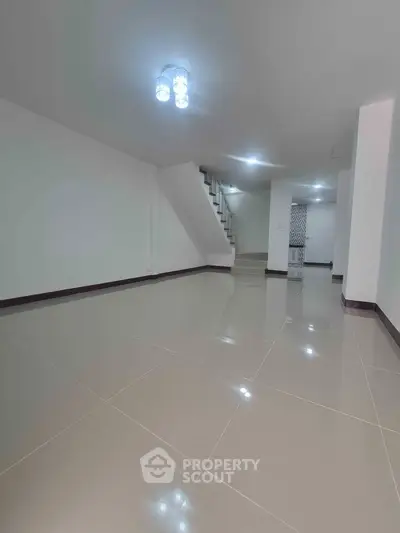 Spacious modern interior with sleek tile flooring and elegant staircase, perfect for stylish living.