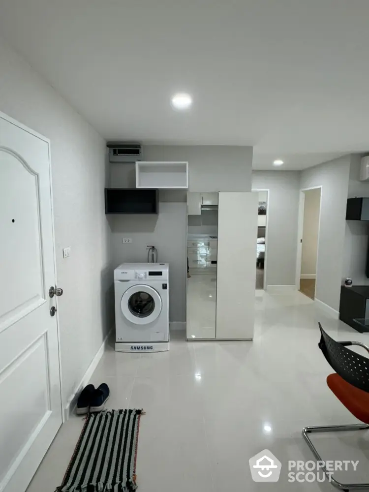 Modern apartment interior with washing machine and sleek storage solutions.