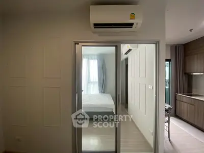 Modern apartment interior with bedroom and kitchen, featuring sleek design and air conditioning.