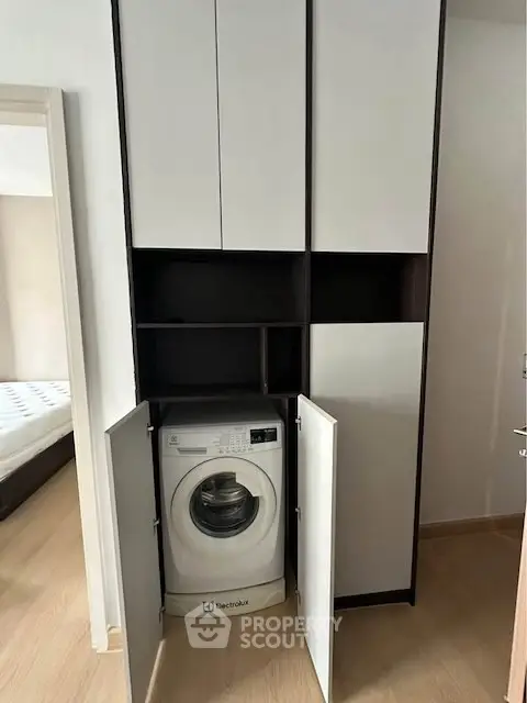 Modern laundry area with built-in washing machine in sleek cabinet design.