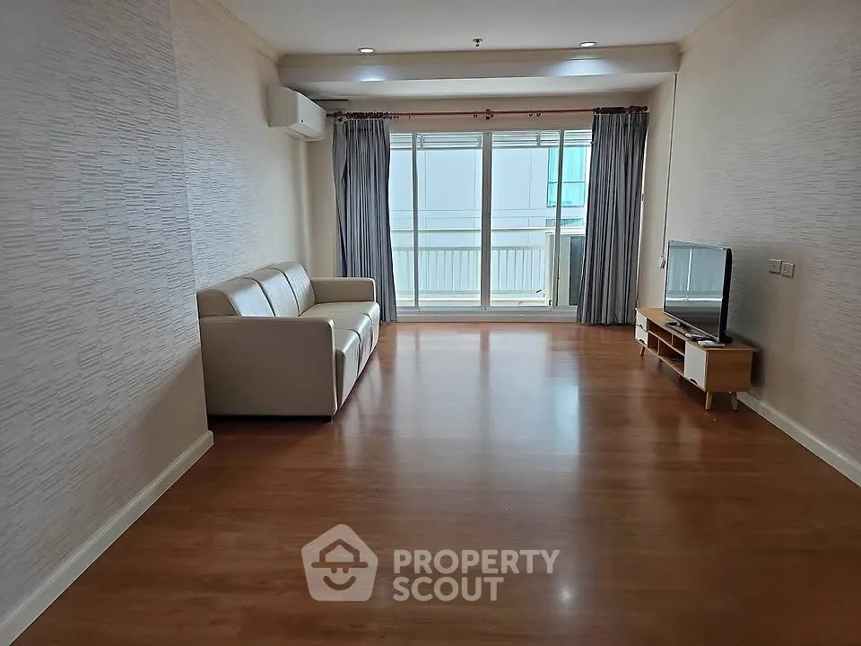 Spacious living room with wooden flooring and large window in modern apartment
