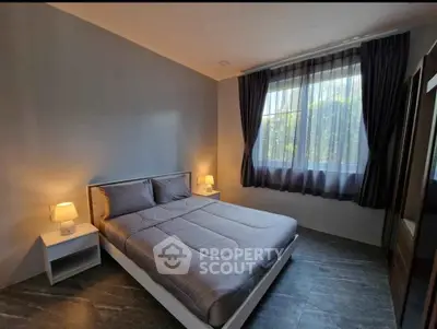 Cozy bedroom with modern decor and ample natural light from large window.