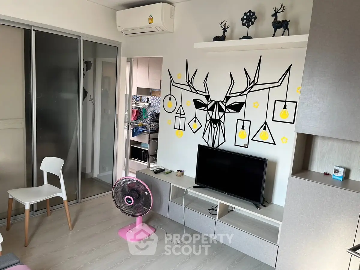 Modern living room with stylish decor and open kitchen layout, featuring a unique wall art and sleek furniture.