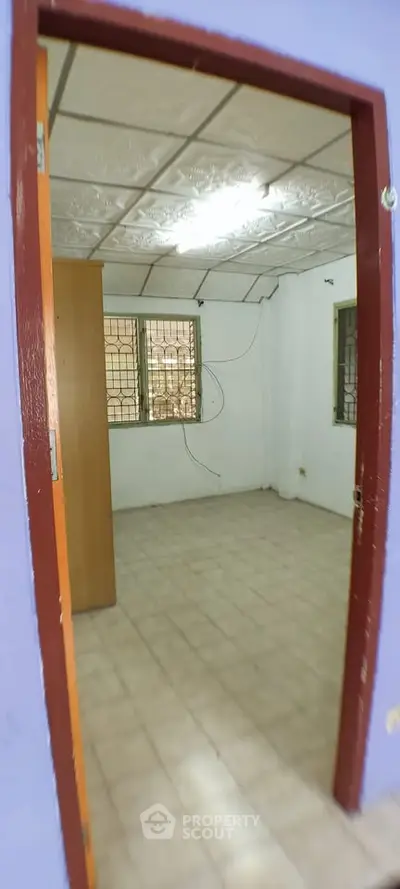 Spacious empty room with tiled floor and barred windows, ideal for customization.