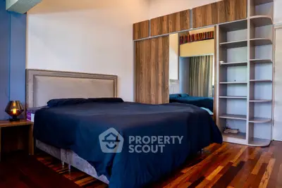 Spacious bedroom with modern wooden flooring and stylish built-in wardrobe.