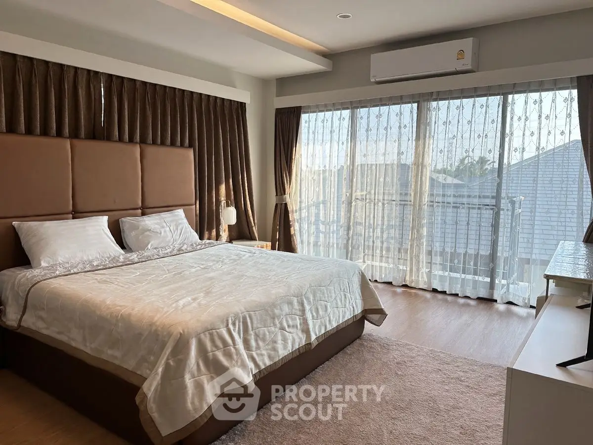 Spacious bedroom with large windows and elegant decor in a modern home.