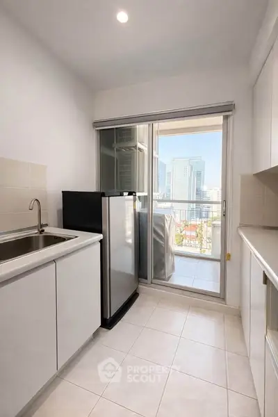 Modern kitchen with sleek cabinetry and balcony view in urban apartment