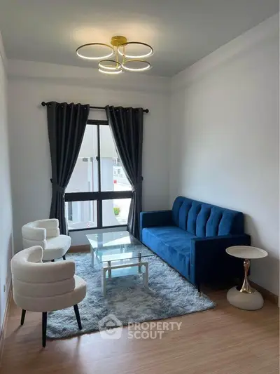 Modern living room with blue sofa, elegant chairs, and stylish lighting