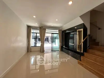Spacious modern living room with large windows and elegant staircase