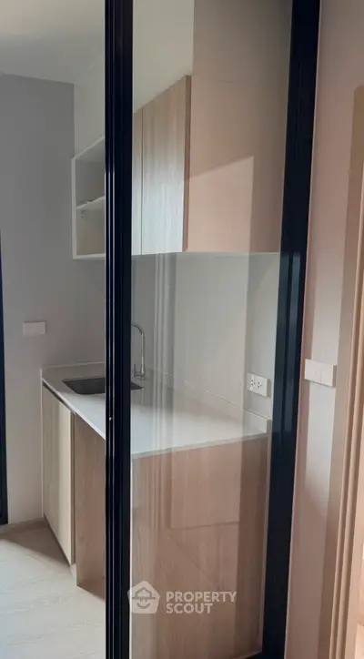 Modern compact kitchen with sleek cabinetry and glass partition