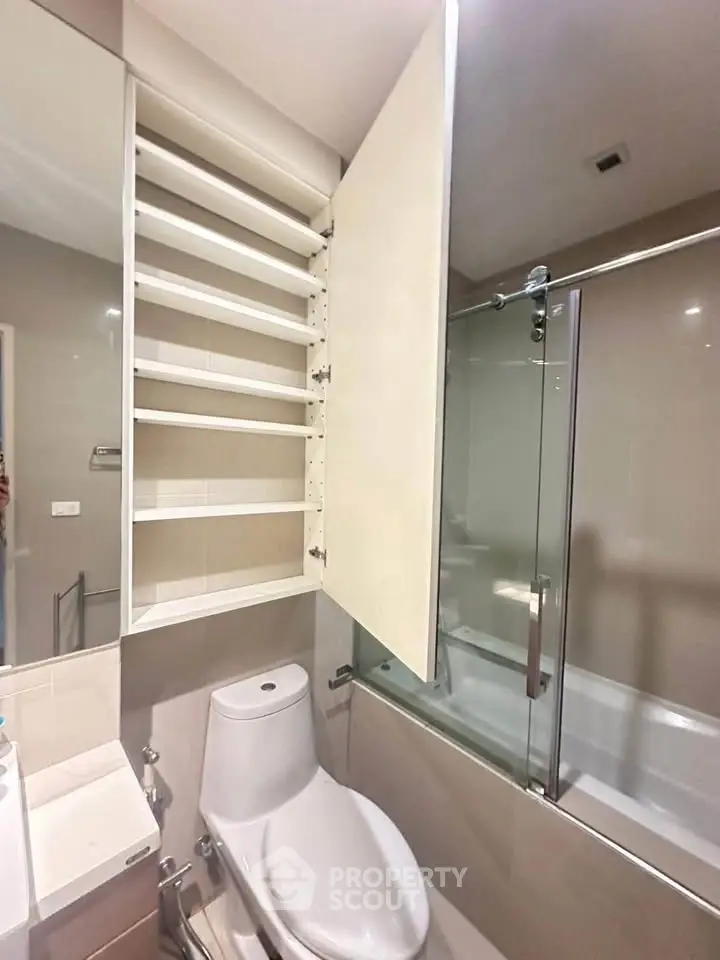 Modern bathroom with sleek storage and glass-enclosed bathtub, perfect for urban living.