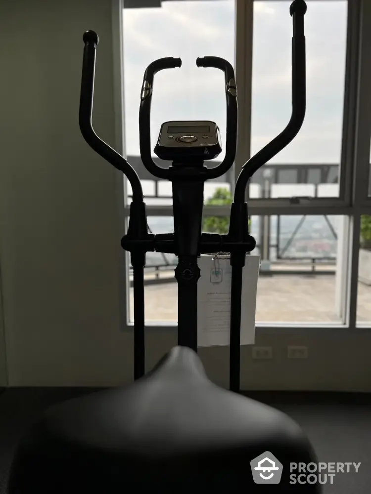 Modern gym with exercise equipment and city view from large windows