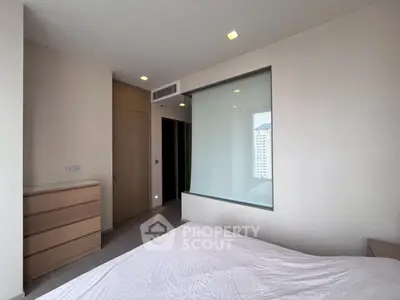 Modern bedroom with minimalist design and large window offering city view
