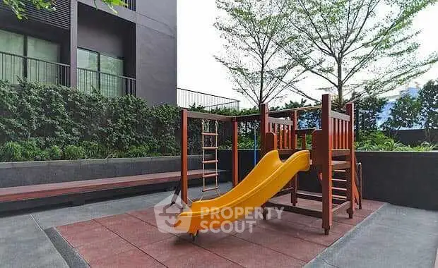 Modern apartment building with outdoor playground and lush greenery.