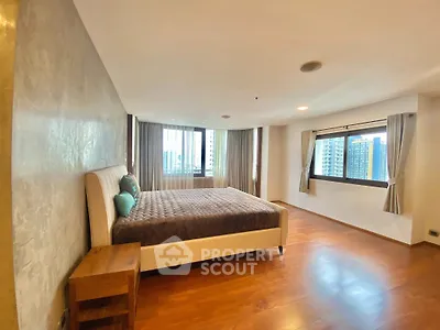 Spacious bedroom with large windows and wooden flooring in modern apartment