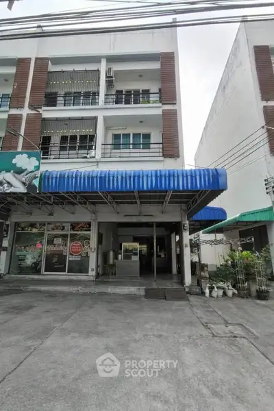 Commercial building with blue awning and large storefront windows in urban setting.