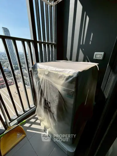 Compact balcony with city view and covered washing machine, ideal for urban living.