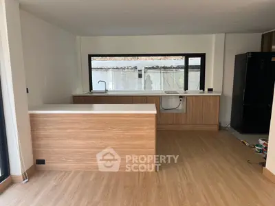 Modern kitchen with sleek wooden cabinetry and large window, perfect for culinary enthusiasts.