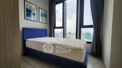 Modern bedroom with large windows offering stunning city views and stylish decor.