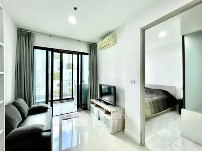 Modern apartment living room with balcony and bedroom view, featuring sleek furniture and bright natural light.