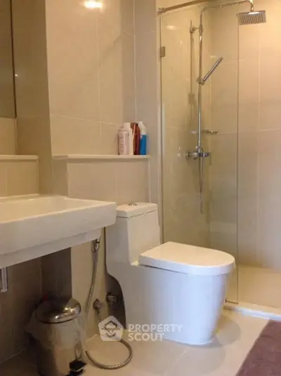Modern bathroom with glass shower and sleek fixtures in contemporary apartment.