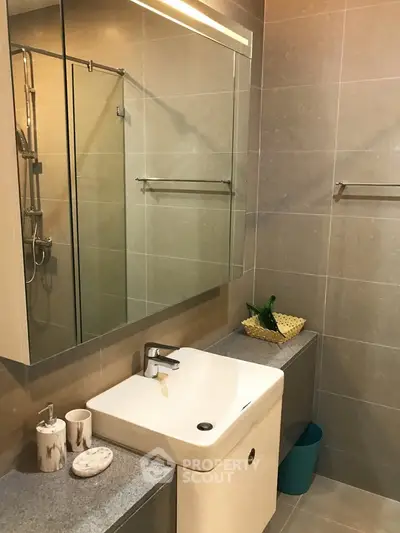 Modern bathroom with sleek fixtures and elegant tile design, featuring a stylish sink and mirror.