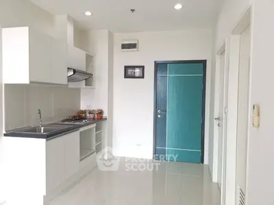 Modern kitchen with sleek white cabinetry and teal door
