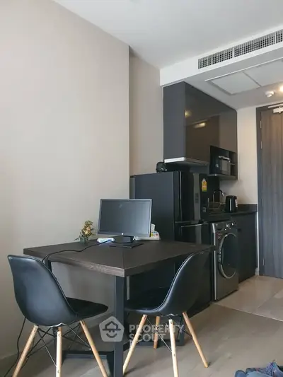 Modern compact kitchen with dining area and appliances in a stylish apartment.