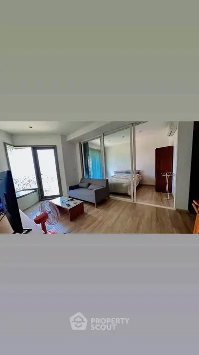 Modern living room with sliding glass doors leading to a cozy bedroom.