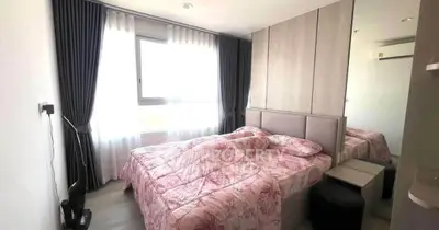 Cozy bedroom with floral bedding and modern decor, featuring large window and mirrored wardrobe.