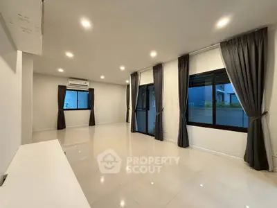 Spacious modern living room with large windows and elegant curtains