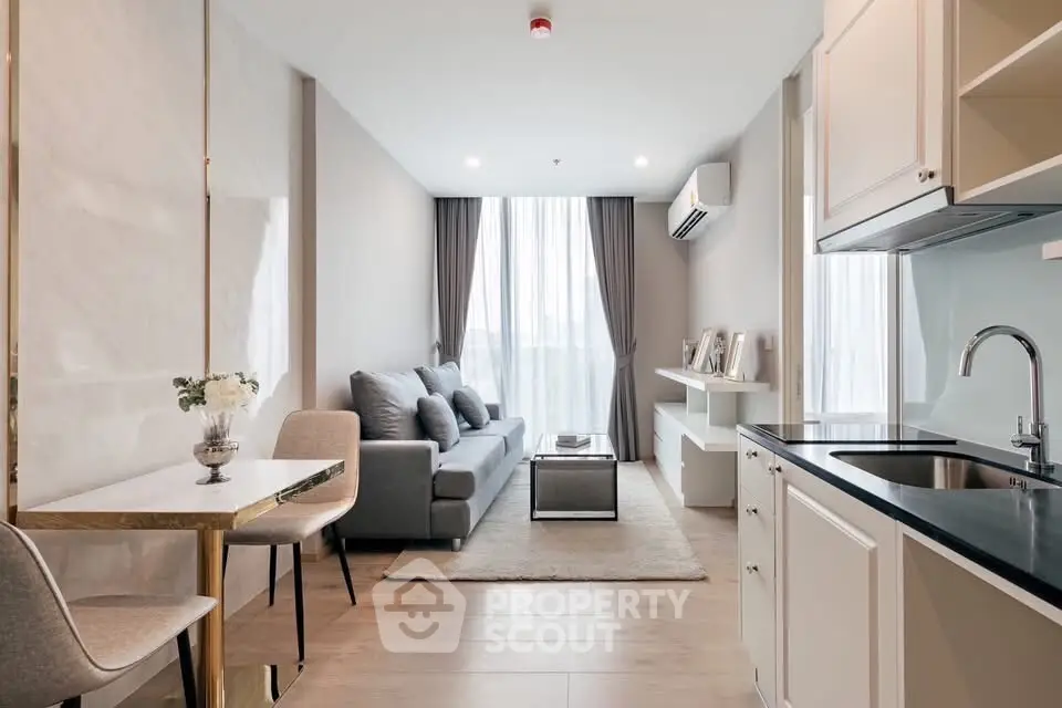 Modern living room with open kitchen, stylish decor, and natural light.