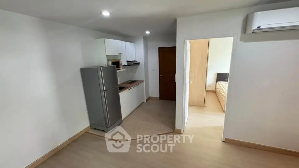 Modern apartment interior with compact kitchen and bedroom view